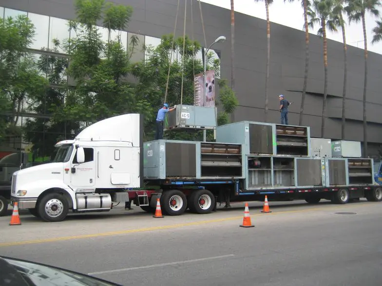 A truck is hauling an air conditioner unit.