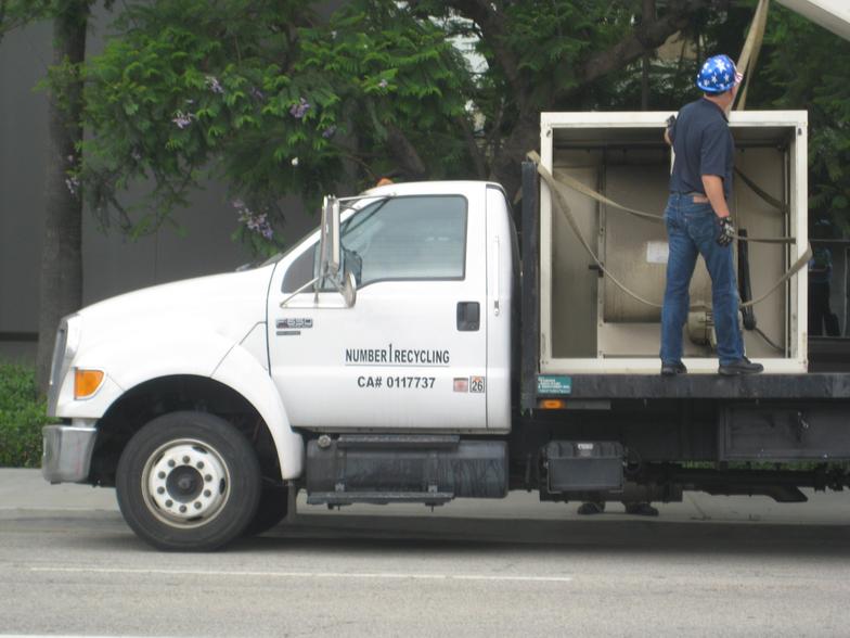 A man standing on the back of a white truck.